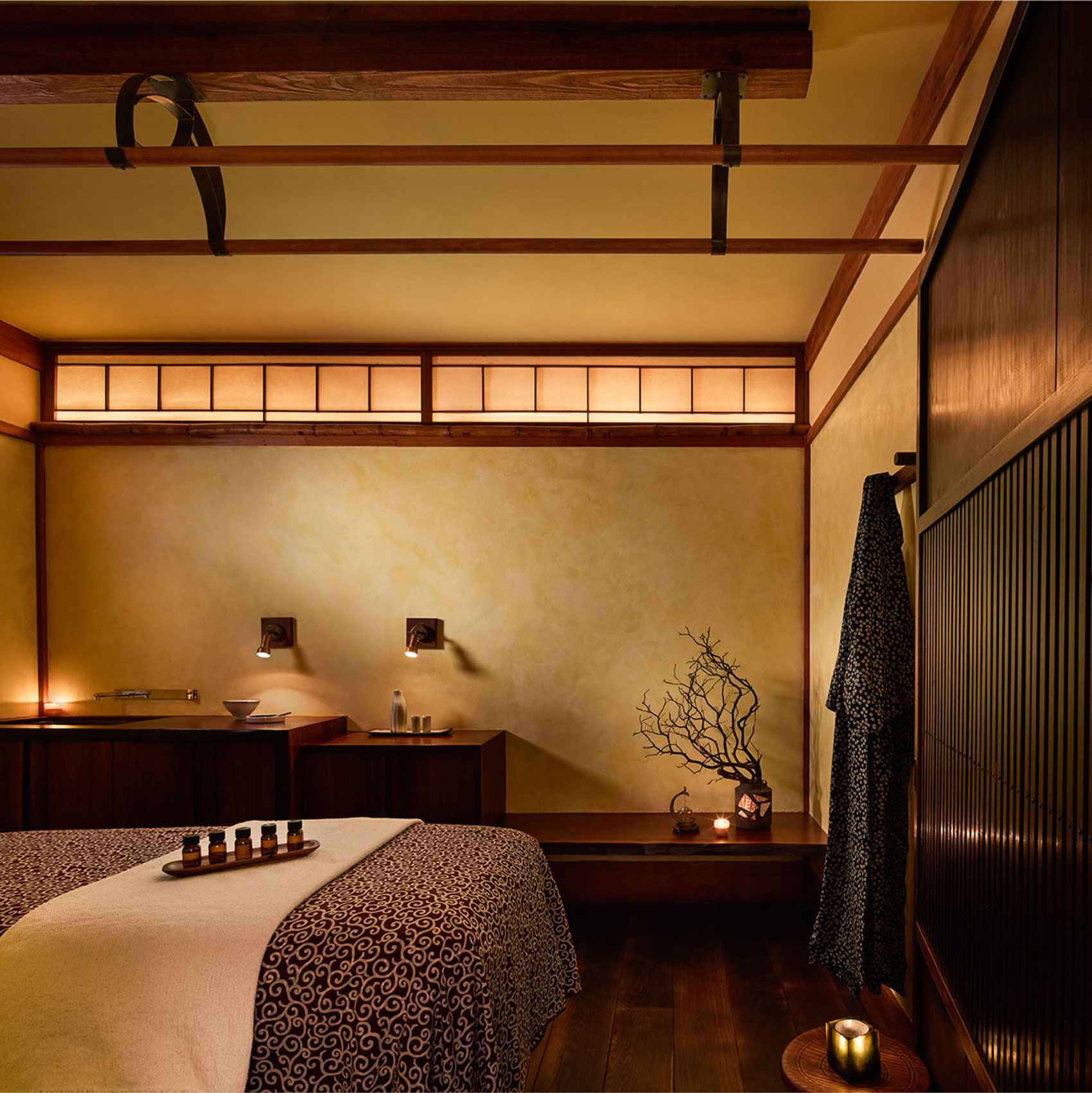 A treatment room inside the Shibui Spa. Tranquil decor, a treatment bed and robe hanging on the wall.